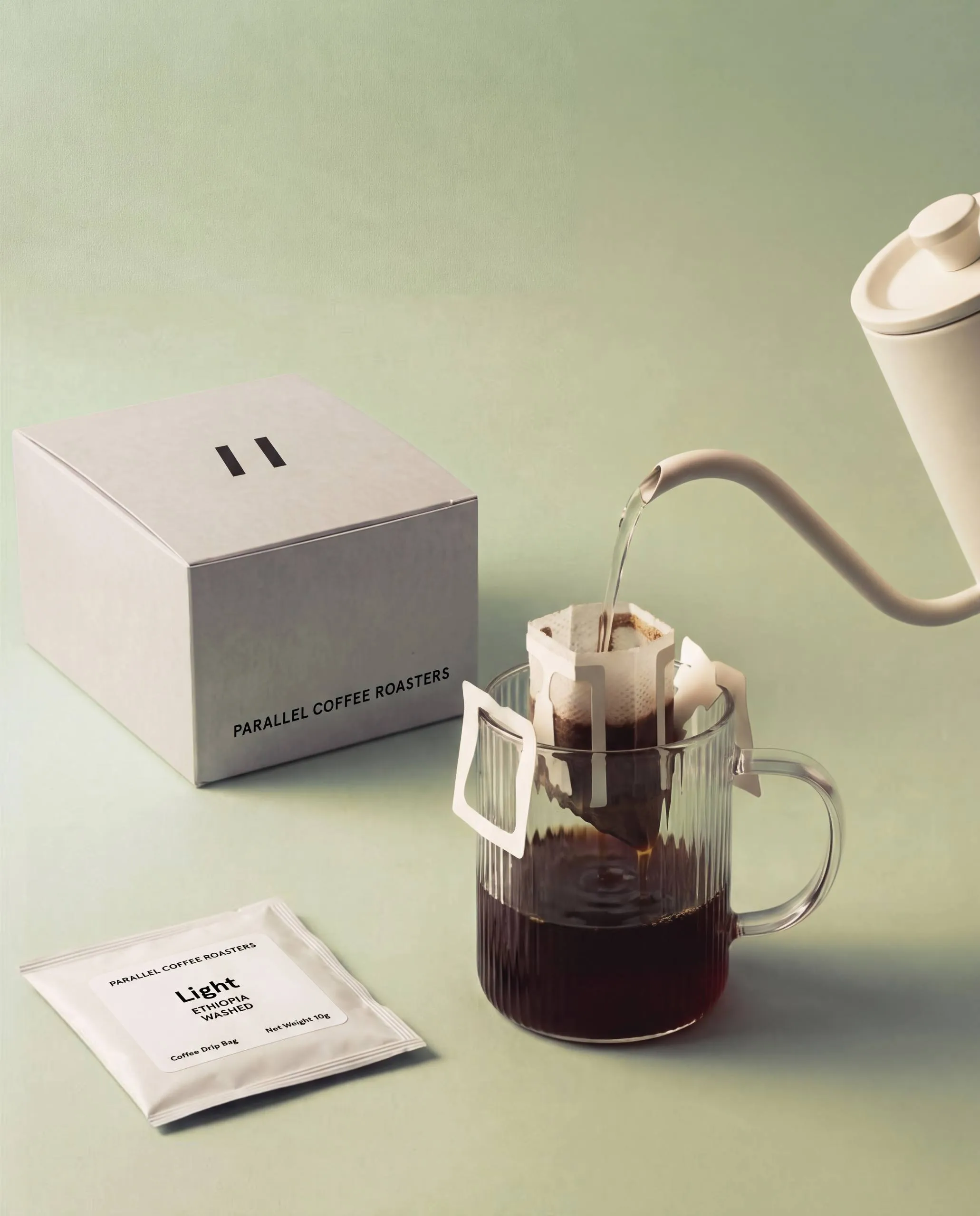 Parallel drip bag box beside a glass mug with a drip bag brewing