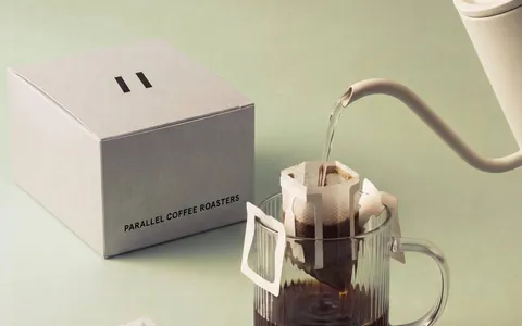 Parallel drip bag box beside a glass mug of brewed coffee