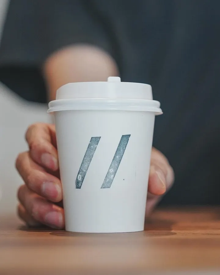 Hand holding a Parallel takeaway cup